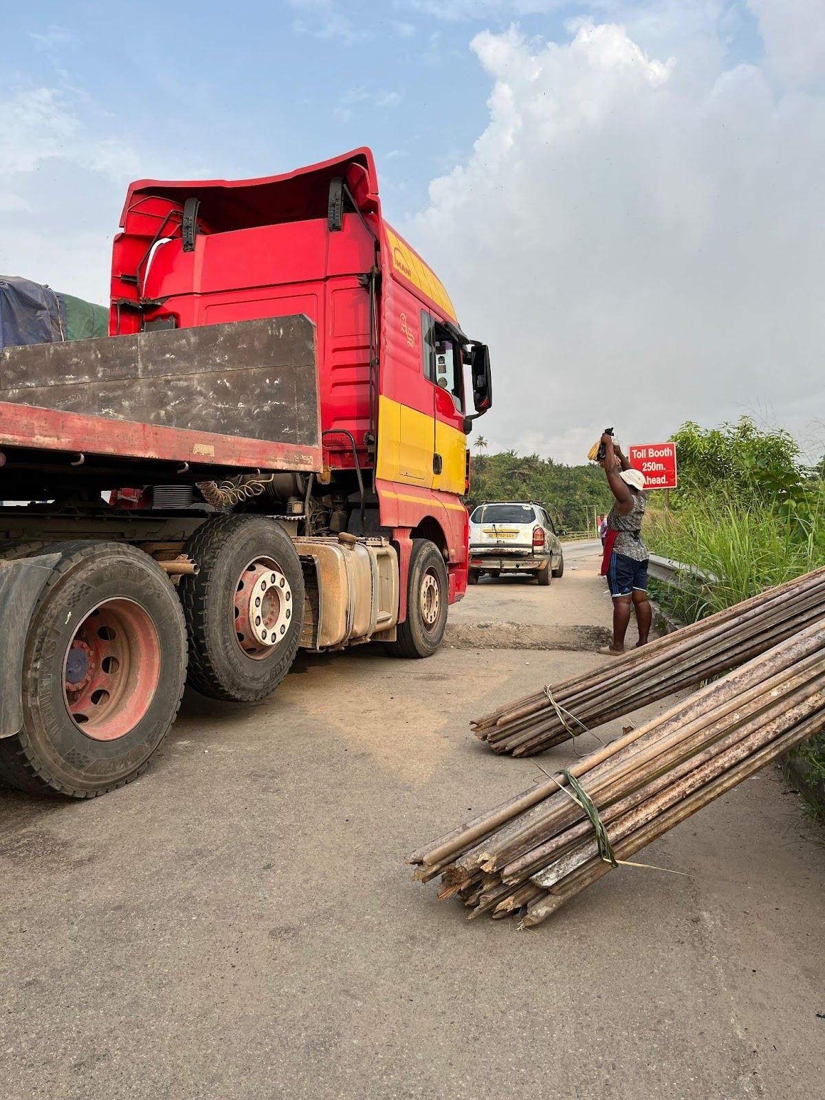 Figure. 3 A woman seller reaching out to the truck driver to sell fried fish, an image that highlights the dynamics between large-scale infrastructure and the everyday realities of local women. (Source: Zaby Sadhoe, 2025)